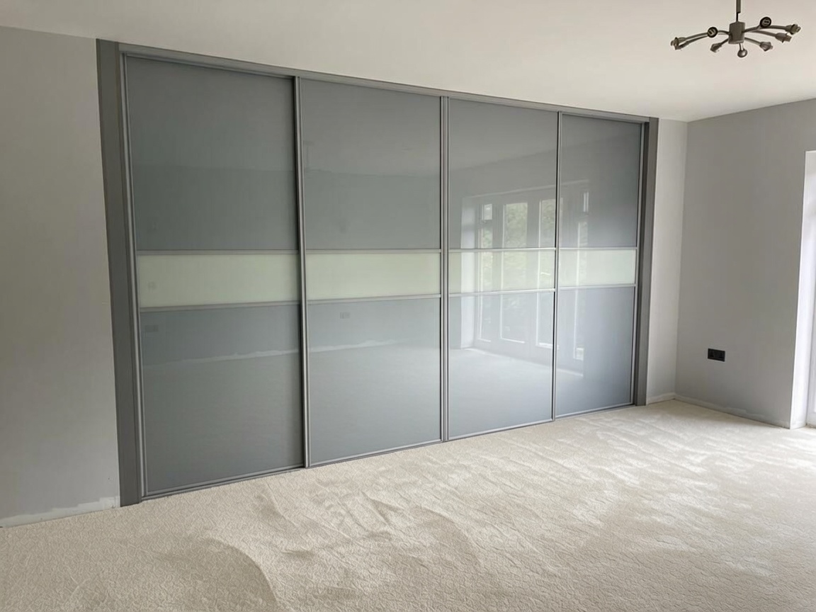 Grey glass sliding wardrobe doors with a white glass band in a South Wales bedroom