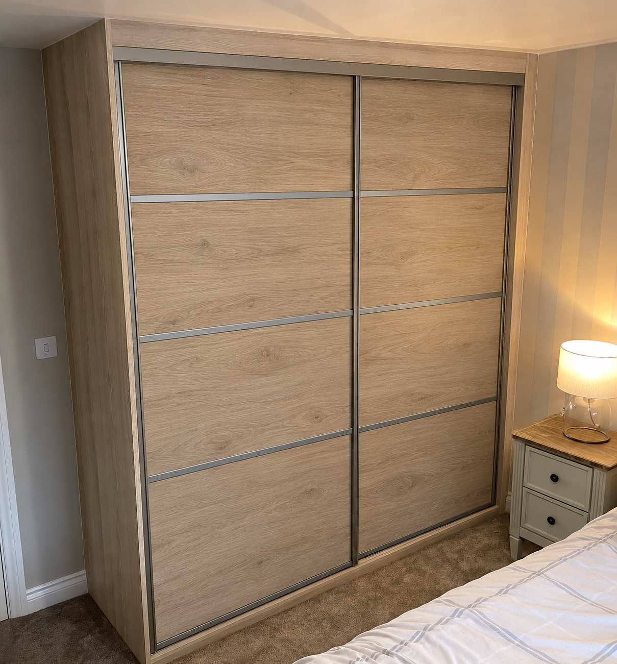 Oak-effect solid panel sliding wardrobe doors with silver horizontal strips in a South Wales bedroom